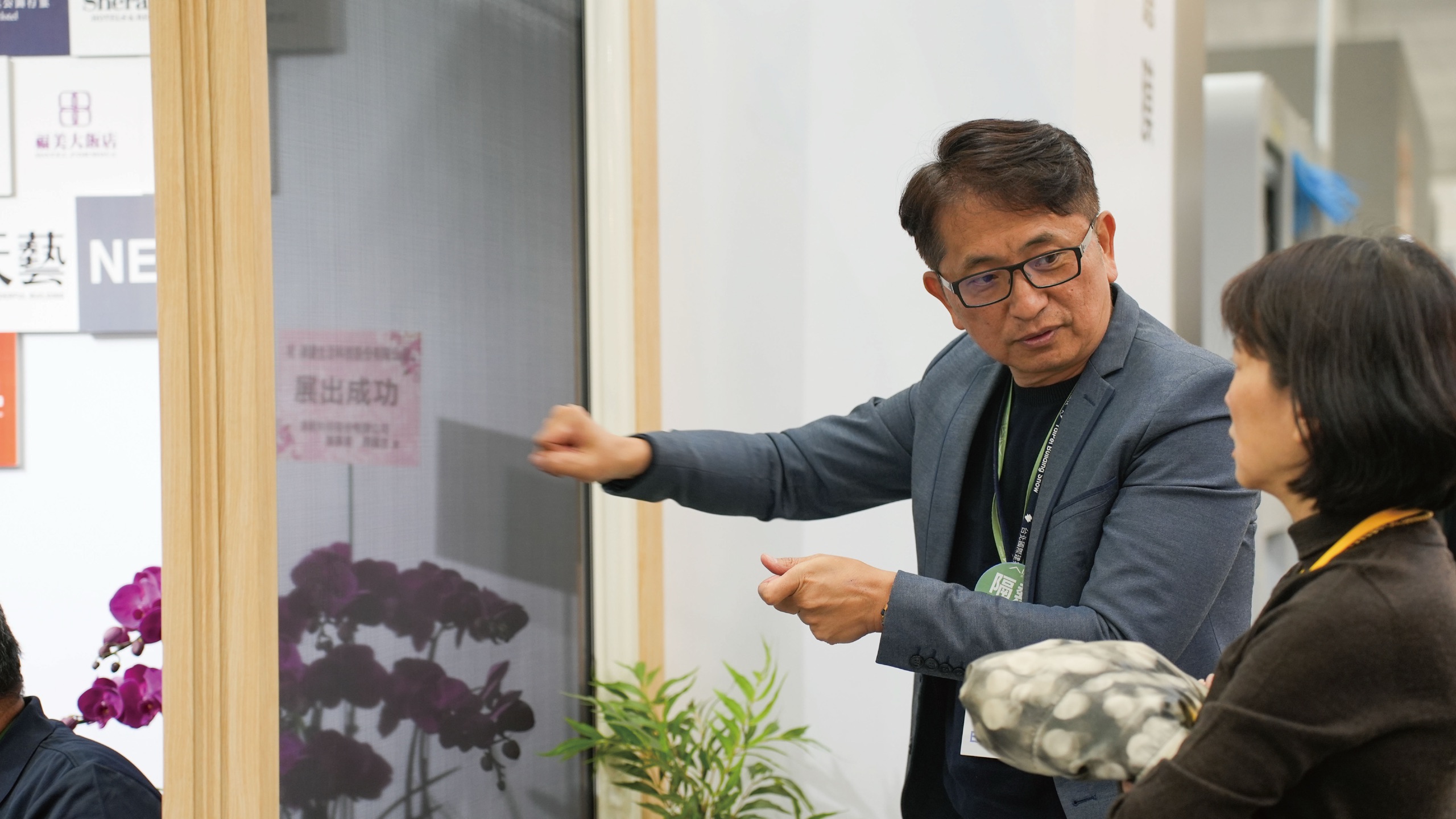 台北建材展 AIM 風光濾膜攤位：人員向參觀者解說貼覆濾膜的窗扇實品